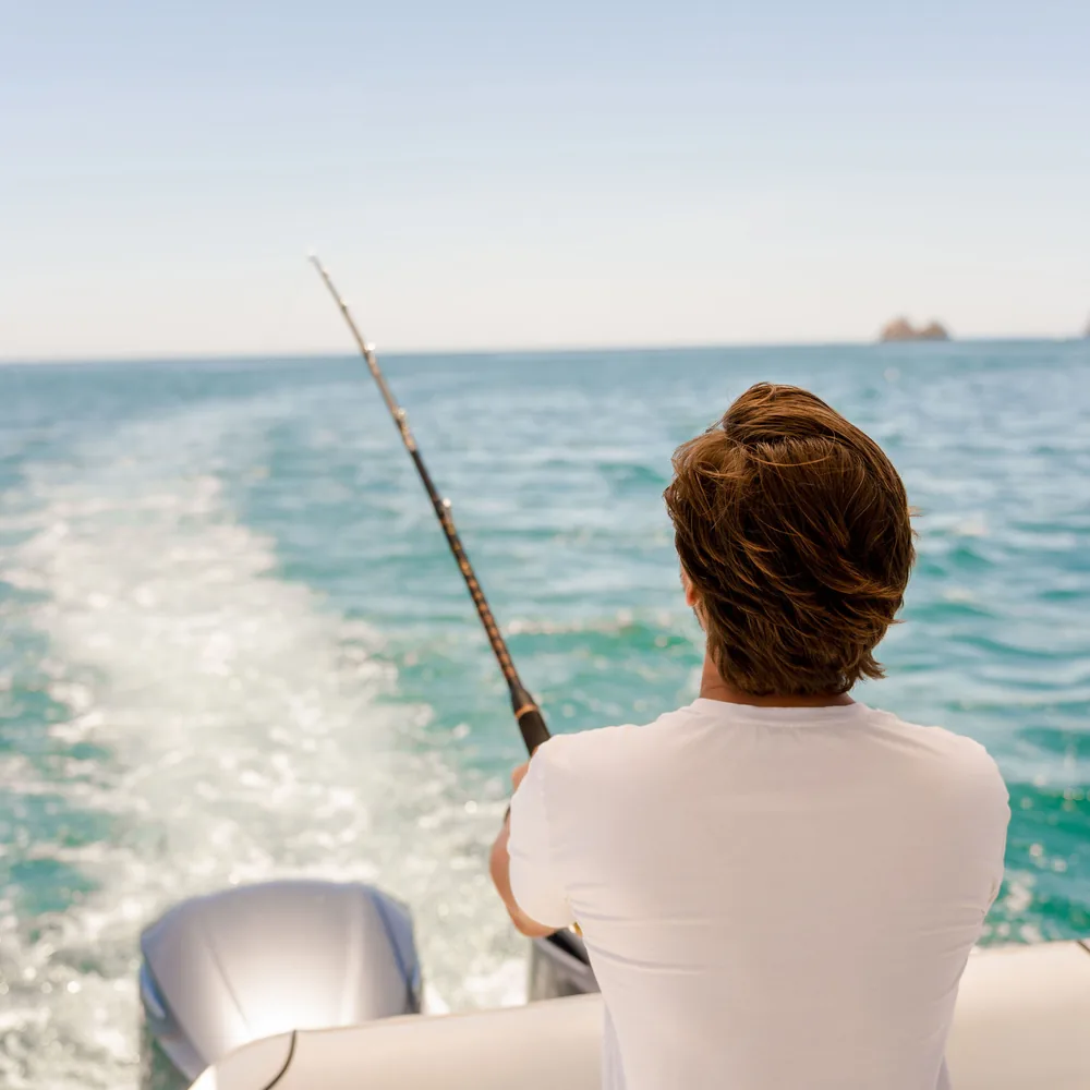 An angler trolling from the stern of an Ocean Club charter boat on the Pacific coast