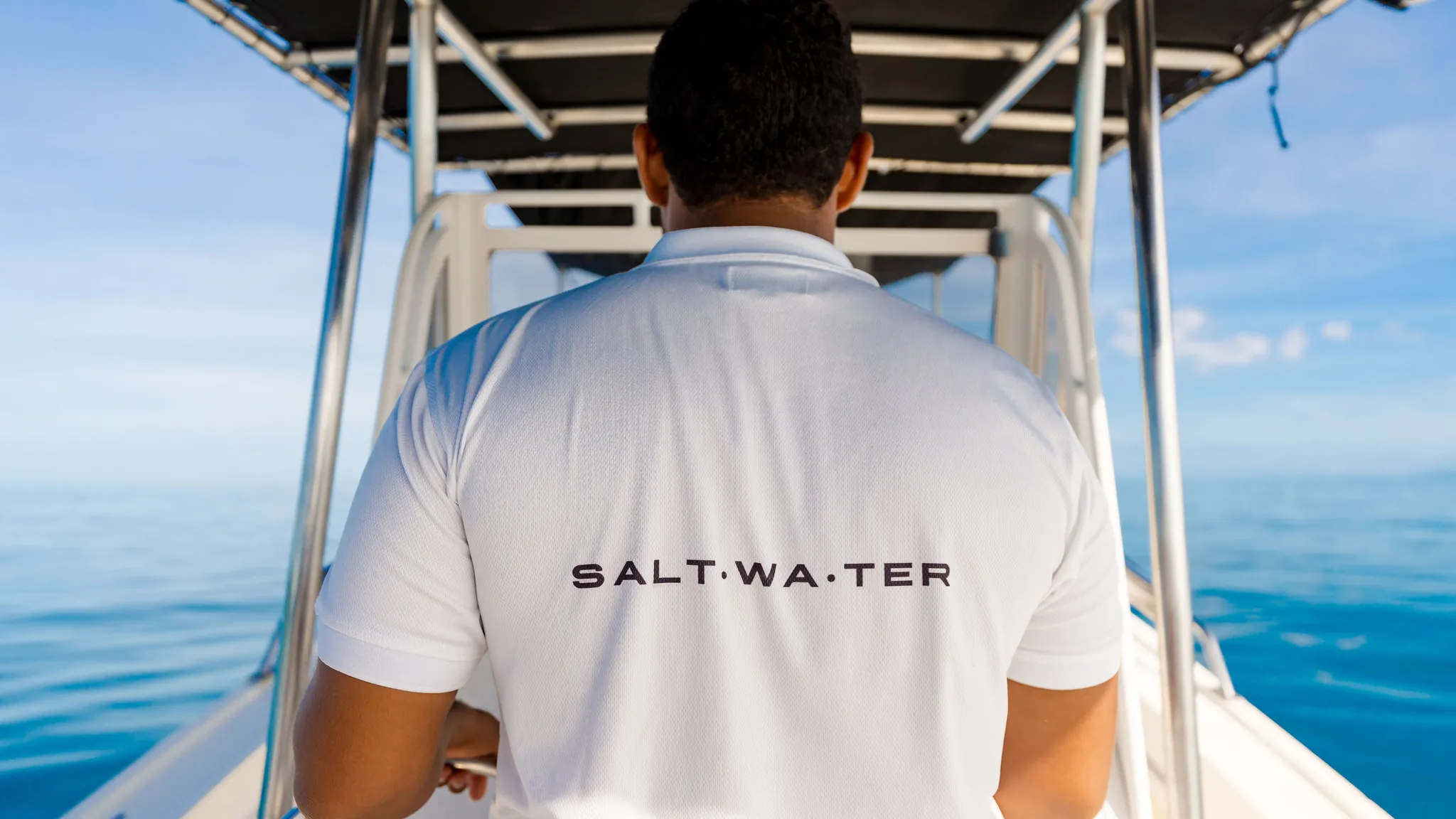 An Ocean Club crew member in a Salt Water shirt at the helm of a charter boat on Costa Rica's Pacific coast