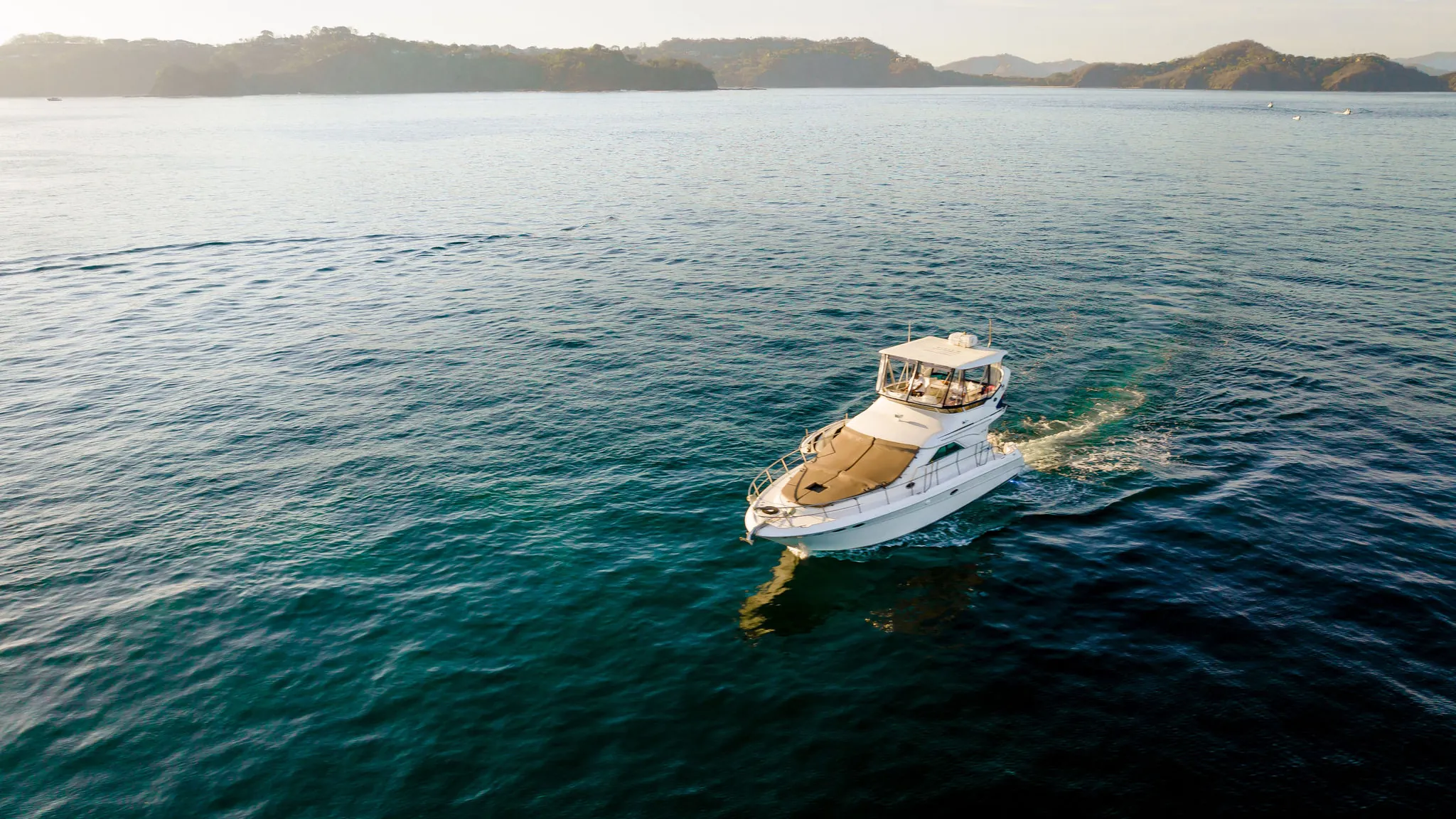 Aerial view looking down on an Ocean Club motor yacht anchored in clear water on Costa Rica's Pacific coast