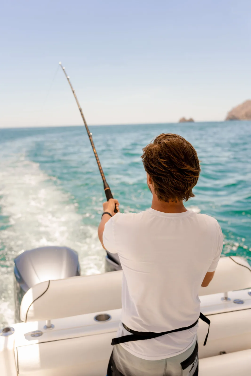 Fishing off Disparate's stern, rod bent into the wake