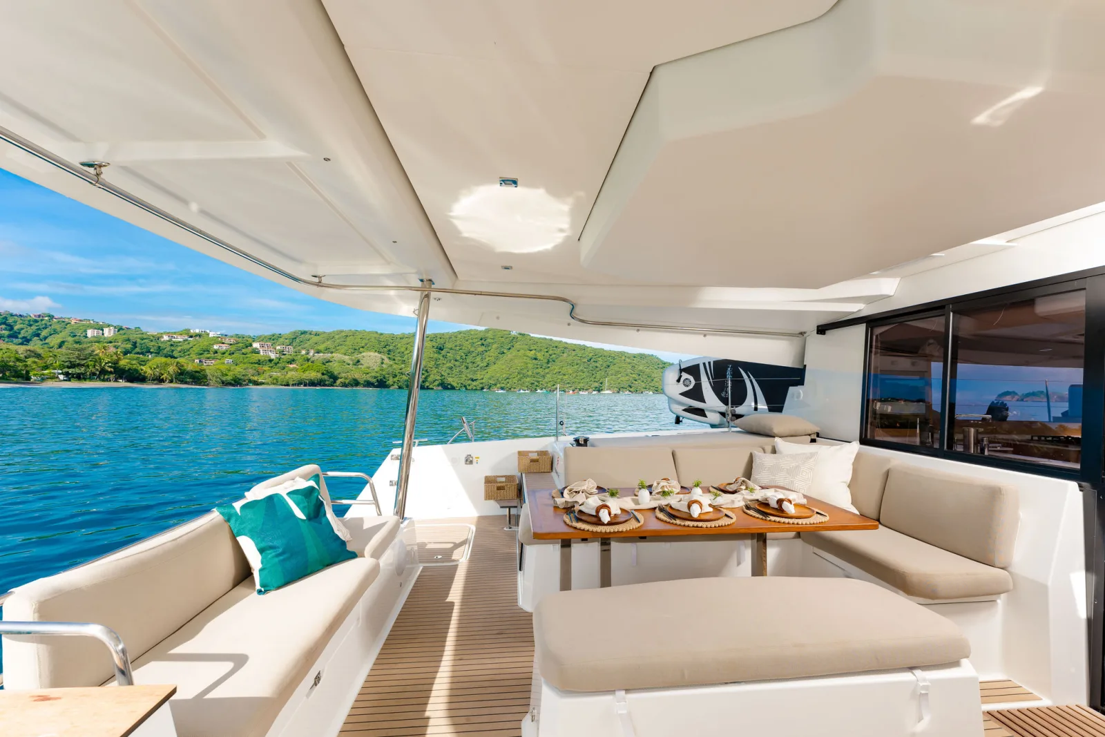 The shaded aft deck aboard Endeavour, cushioned seating looking out over the water to a green headland