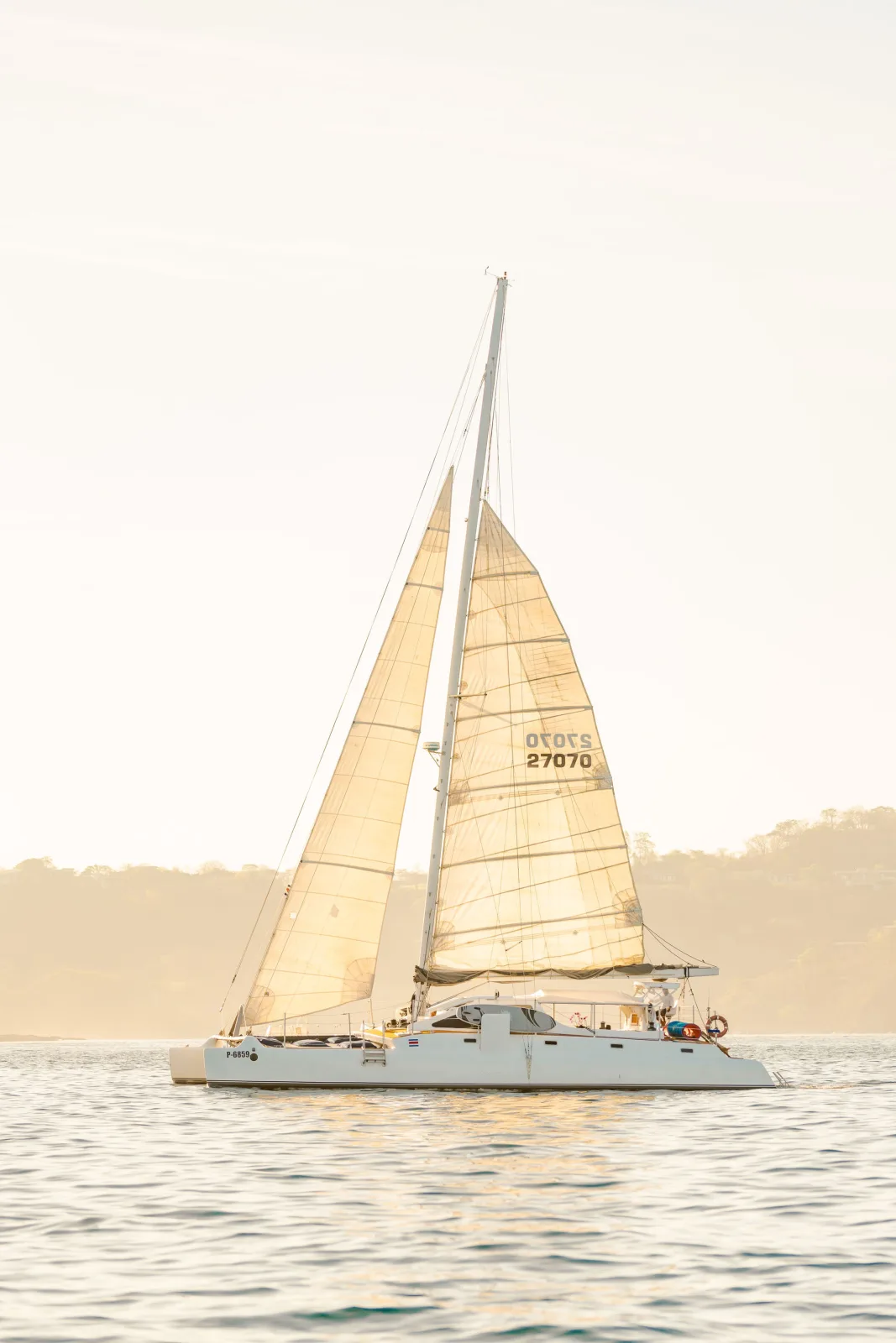 Lohe Lani's foredeck lined with sun loungers, mast rising into a bright sky