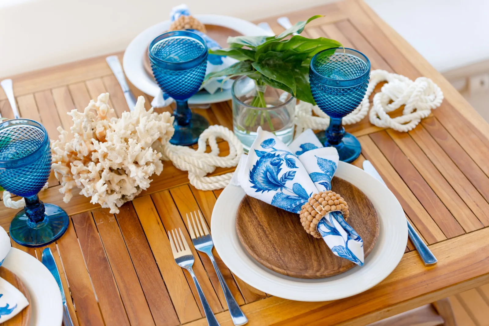 A place setting aboard Sea Ya — blue linen and coral on teak