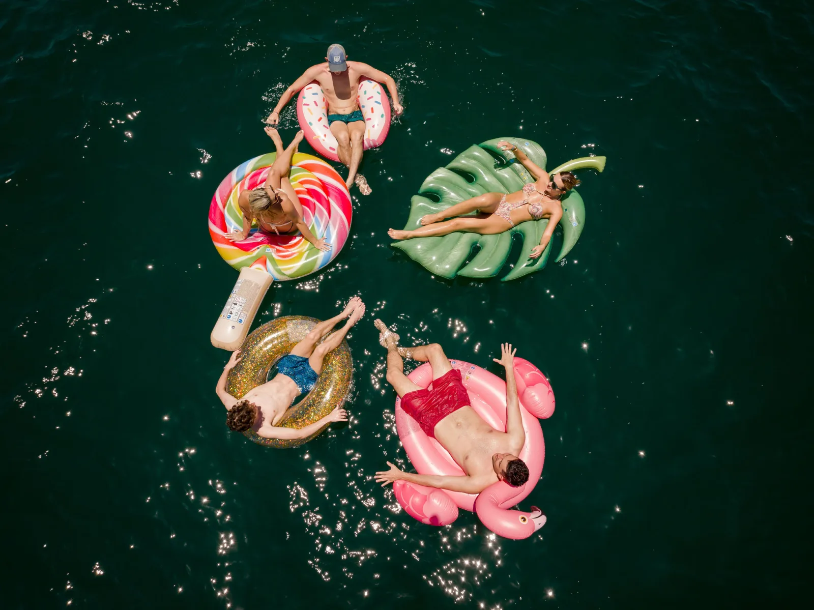 Guests on inflatable floats in clear water, seen from above