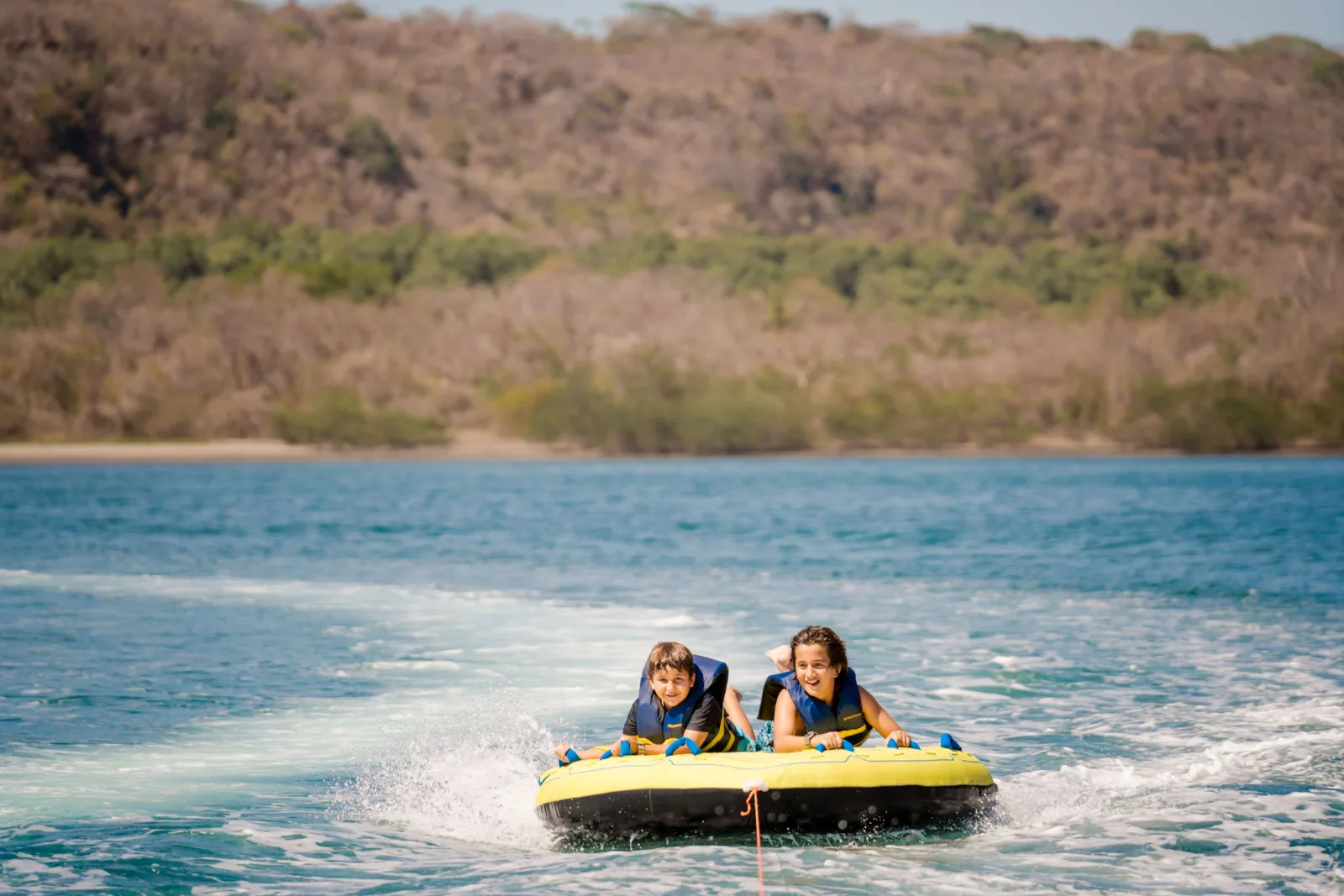 Two guests riding a towable behind the tender